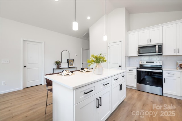 kitchen featuring a center island, backsplash, decorative light fixtures, white cabinetry, and stainless steel appliances