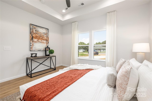 bedroom featuring a tray ceiling, ceiling fan, and light hardwood / wood-style floors