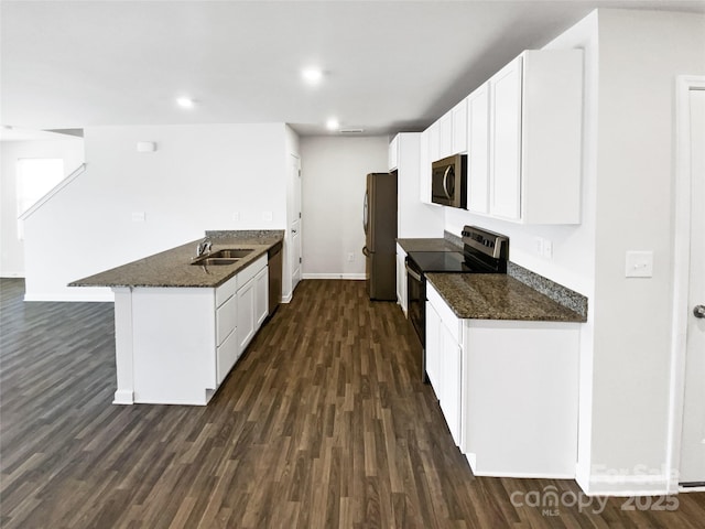 kitchen featuring dark stone countertops, dark hardwood / wood-style flooring, white cabinets, and stainless steel appliances