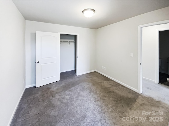 unfurnished bedroom with dark colored carpet and a closet