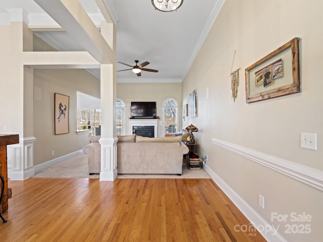 living area featuring light wood-type flooring, a fireplace, baseboards, and a ceiling fan