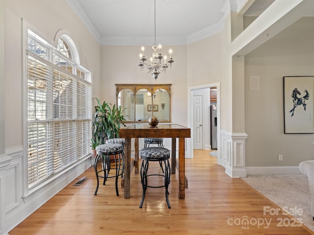 dining room with ornamental molding, light wood-type flooring, a healthy amount of sunlight, and visible vents