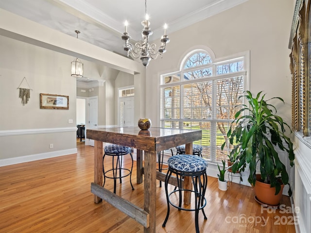 dining room with baseboards, crown molding, light wood-type flooring, and a notable chandelier