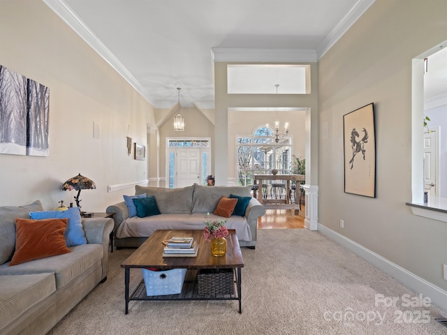 carpeted living room featuring baseboards, ornamental molding, and a notable chandelier