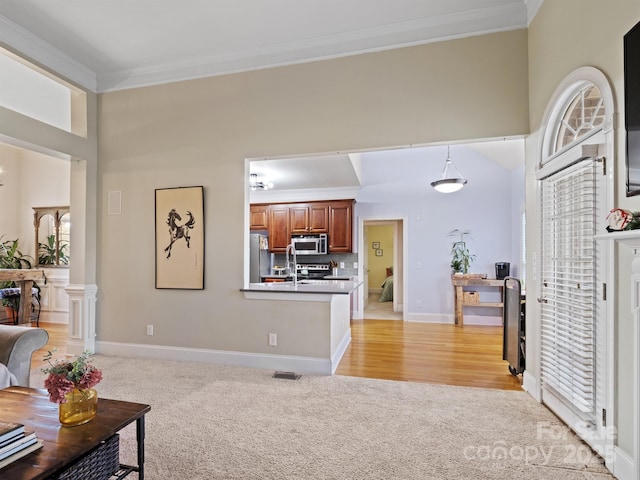 living room featuring light colored carpet, a towering ceiling, baseboards, visible vents, and ornamental molding