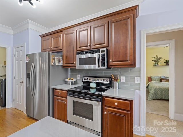 kitchen with brown cabinetry, decorative backsplash, appliances with stainless steel finishes, ornamental molding, and light countertops