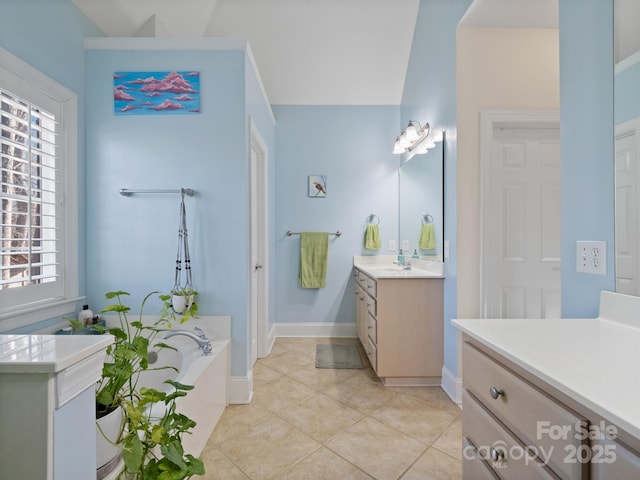 bathroom with tile patterned flooring, a garden tub, vanity, and baseboards