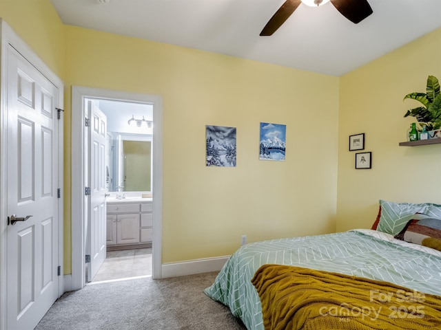 bedroom with baseboards, connected bathroom, light colored carpet, ceiling fan, and a sink