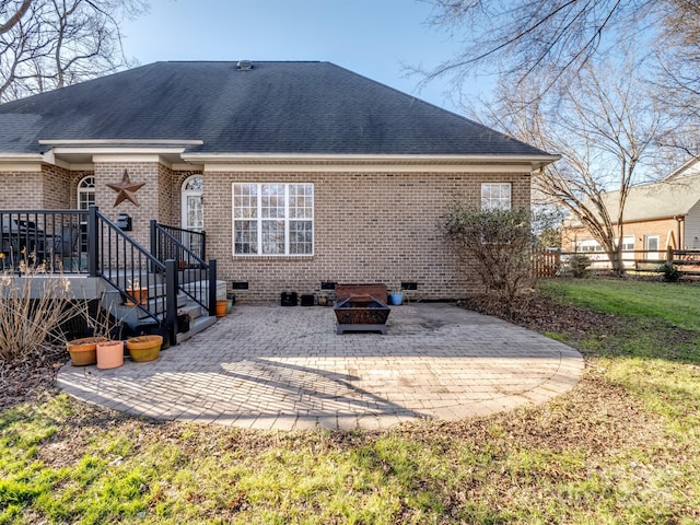 rear view of property featuring a patio, an outdoor fire pit, brick siding, crawl space, and roof with shingles