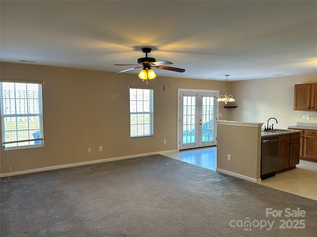 kitchen with light carpet, french doors, ceiling fan with notable chandelier, stainless steel dishwasher, and decorative light fixtures