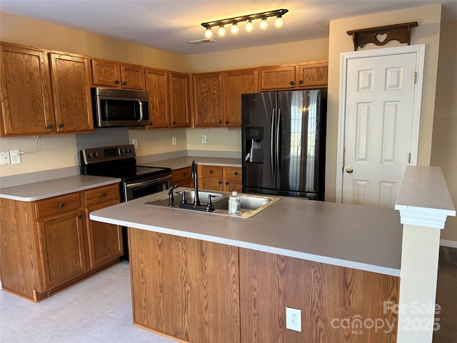 kitchen featuring appliances with stainless steel finishes, a center island with sink, and sink