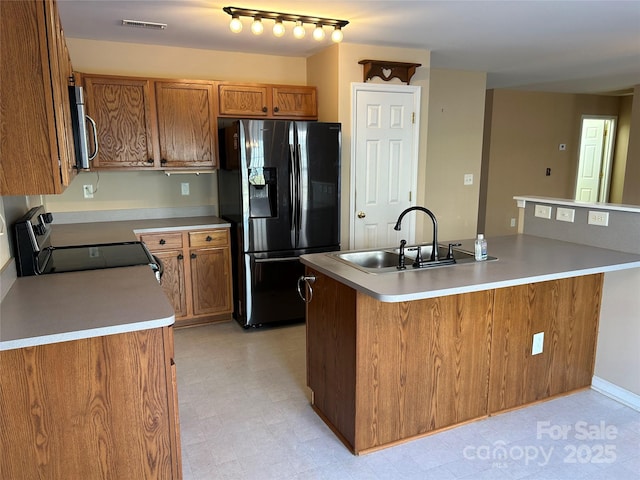 kitchen featuring a center island with sink, electric range oven, sink, and black refrigerator with ice dispenser