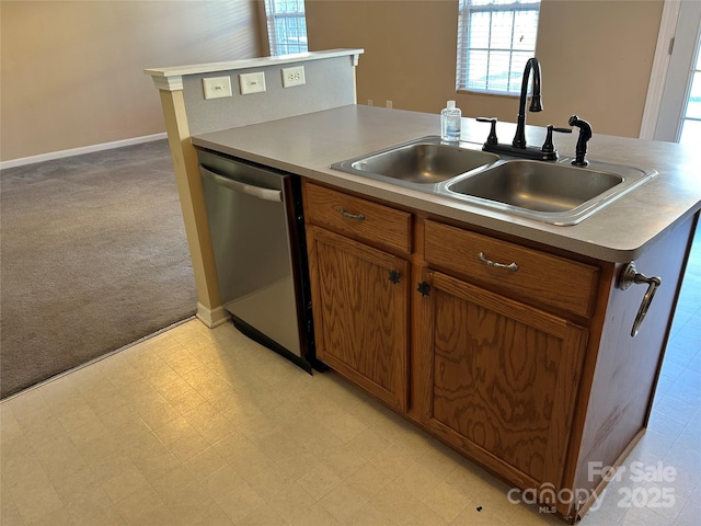 kitchen featuring dishwasher, an island with sink, light colored carpet, and sink