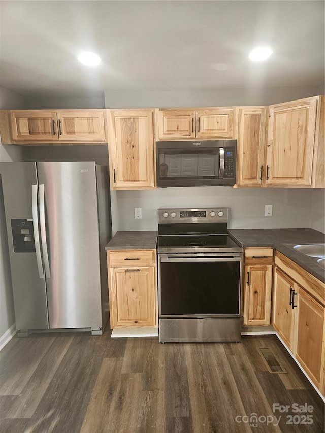 kitchen featuring dark wood-type flooring, stainless steel appliances, and light brown cabinets