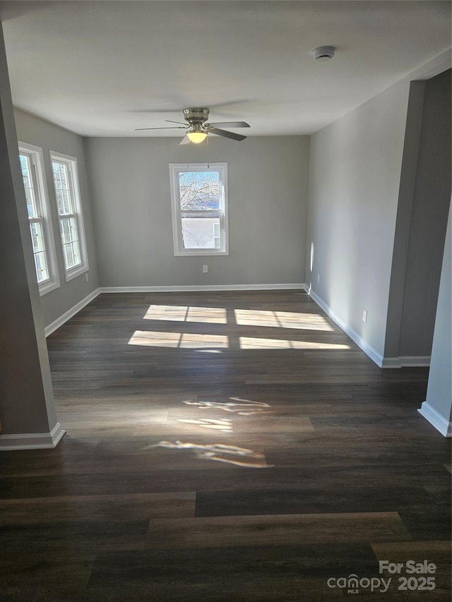 empty room featuring dark hardwood / wood-style floors, a wealth of natural light, and ceiling fan