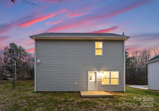 back house at dusk featuring a yard