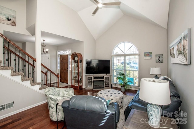 living room featuring dark hardwood / wood-style flooring, high vaulted ceiling, and ceiling fan with notable chandelier