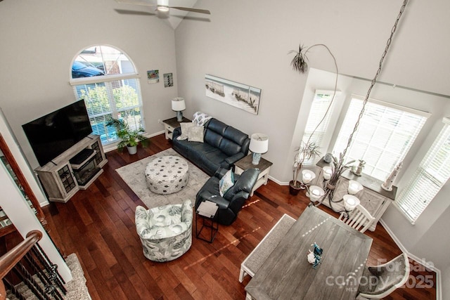 living room featuring ceiling fan with notable chandelier, dark hardwood / wood-style flooring, and a towering ceiling