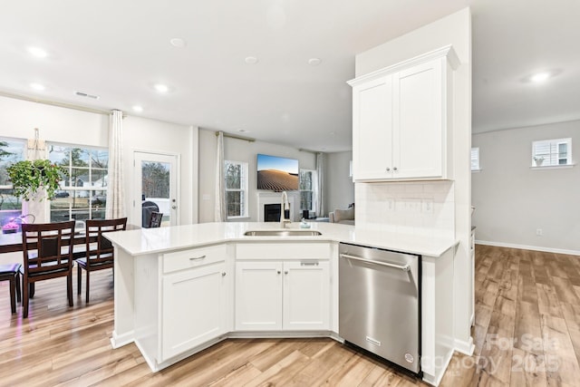 kitchen featuring white cabinets, dishwasher, kitchen peninsula, and sink