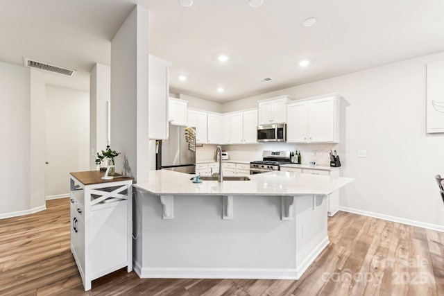 kitchen with a kitchen bar, white cabinetry, sink, and appliances with stainless steel finishes