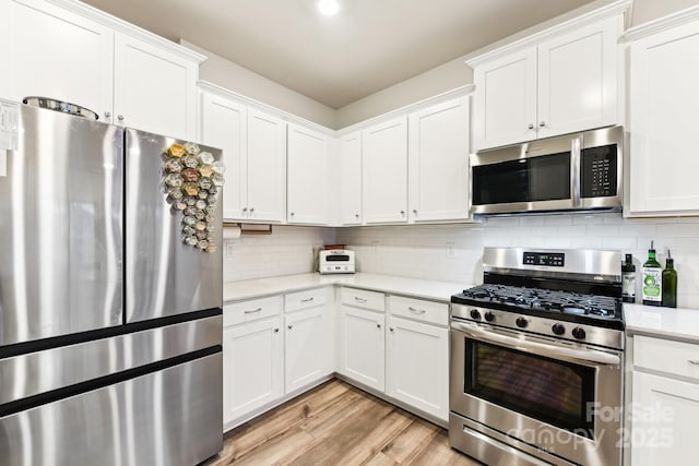 kitchen featuring appliances with stainless steel finishes, light wood-type flooring, tasteful backsplash, and white cabinetry