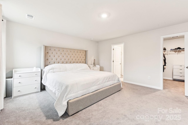 carpeted bedroom with a walk in closet and a closet