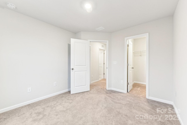 unfurnished bedroom featuring light colored carpet, a spacious closet, and a closet