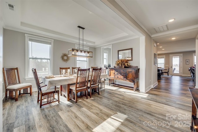 dining area featuring crown molding, a tray ceiling, and light hardwood / wood-style floors