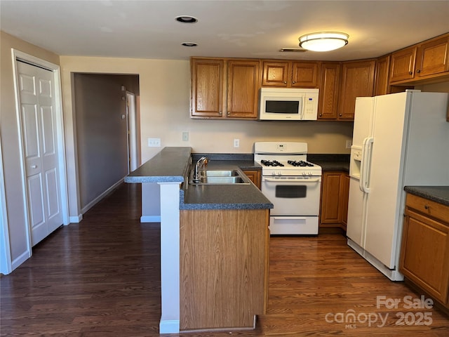 kitchen with kitchen peninsula, dark hardwood / wood-style flooring, sink, and white appliances