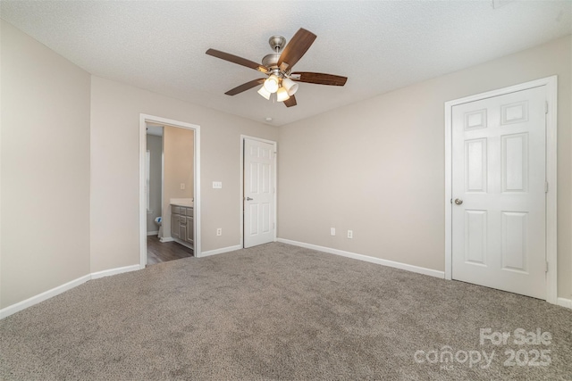 unfurnished bedroom with connected bathroom, dark carpet, a textured ceiling, and ceiling fan