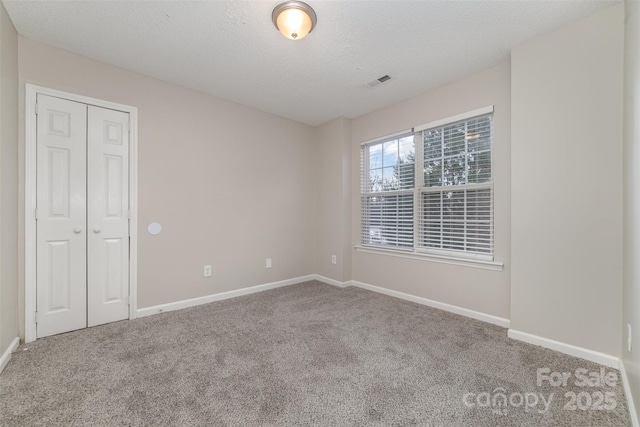 carpeted empty room with a textured ceiling