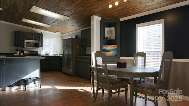 dining room with light wood-type flooring, lofted ceiling, a wealth of natural light, and crown molding