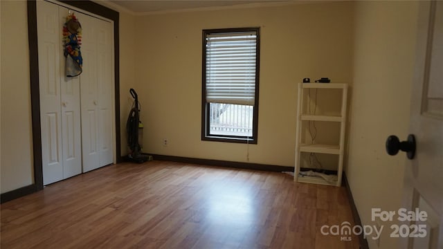 unfurnished bedroom with crown molding, a closet, and hardwood / wood-style flooring