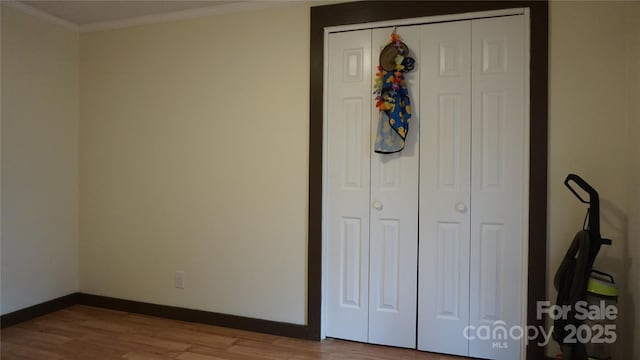 unfurnished bedroom featuring light hardwood / wood-style floors, ornamental molding, and a closet