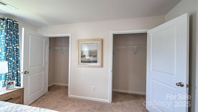 unfurnished bedroom with multiple closets, baseboards, light carpet, and visible vents