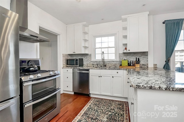 kitchen featuring dark stone counters, white cabinets, sink, wall chimney exhaust hood, and stainless steel appliances