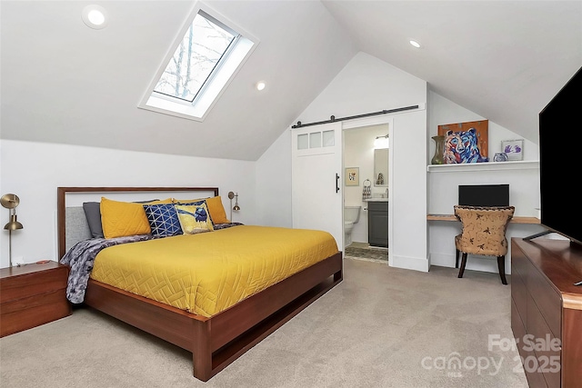 bedroom featuring carpet, ensuite bathroom, a barn door, and lofted ceiling with skylight