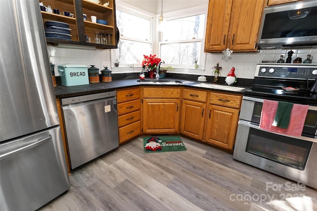 kitchen with light wood-type flooring, stainless steel appliances, tasteful backsplash, and sink