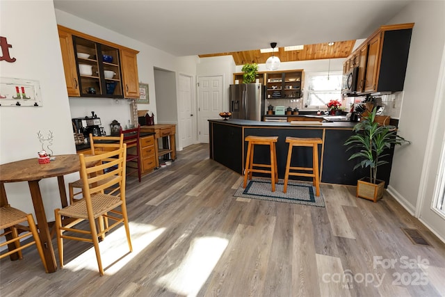 kitchen with decorative light fixtures, light hardwood / wood-style floors, kitchen peninsula, and stainless steel appliances