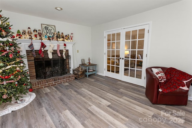 living room with a brick fireplace, wood-type flooring, and french doors