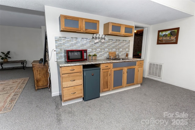 kitchen with light carpet, backsplash, a textured ceiling, sink, and fridge