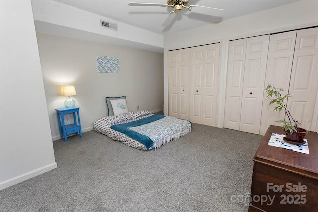 bedroom with carpet flooring, ceiling fan, and two closets