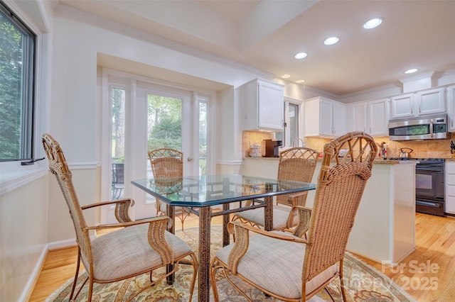 dining space with light hardwood / wood-style flooring and crown molding