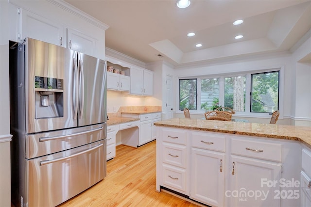 kitchen featuring a tray ceiling, white cabinetry, stainless steel refrigerator with ice dispenser, and light wood-type flooring