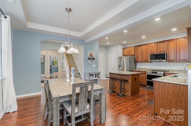 kitchen with decorative light fixtures, sink, a center island, light stone counters, and stainless steel appliances