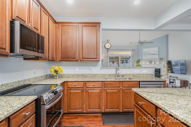 kitchen featuring sink, dark hardwood / wood-style floors, ceiling fan, stainless steel appliances, and light stone countertops