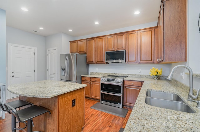 kitchen featuring light stone countertops, appliances with stainless steel finishes, sink, and a breakfast bar