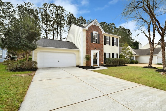 colonial-style house featuring brick siding, a chimney, an attached garage, a front yard, and driveway