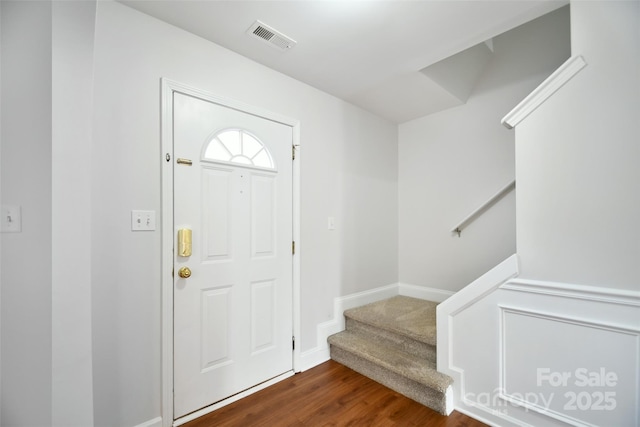 foyer entrance with baseboards, stairs, visible vents, and dark wood-type flooring