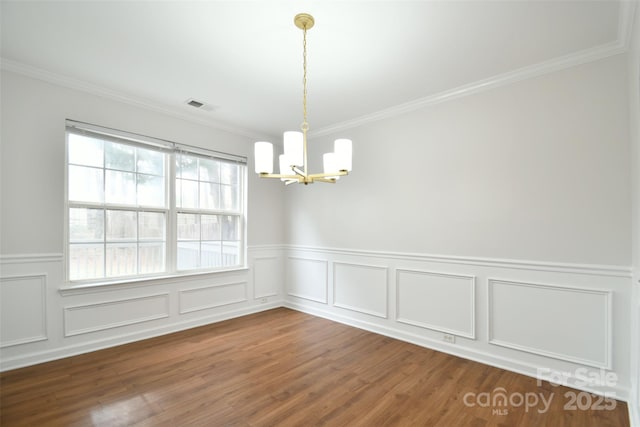 unfurnished dining area featuring crown molding, hardwood / wood-style floors, and a chandelier